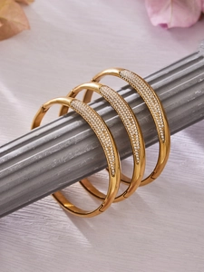 Gros plan de trois bracelets en acier inoxydable plaqué or 18 carats avec oxydes de zirconium