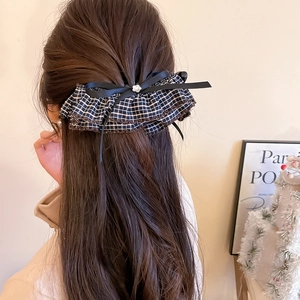 Detail showing checkered ruffled hair clip with black ribbon bow on brown hair