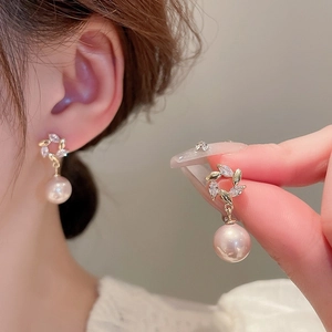 Detail of gold wreath earring with clear crystals and a white hanging pearl