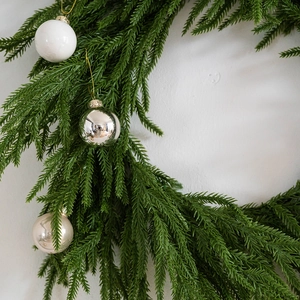 Green Christmas wreath with silver and white ornaments on a clean white background