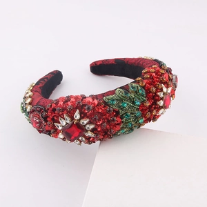 Close-up of red velvet headband with rhinestones and green sequin leaf patterns