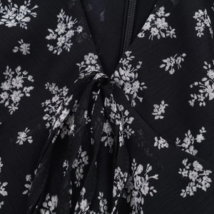 Detail of V-neckline with white floral print on black chiffon fabric and front tie strings