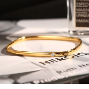 Minimalist square gold titanium steel bracelet with cubic zirconia on a fashion magazine