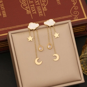 Golden cloud earrings with star moon tassel pendants on a beige jewelry box