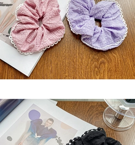 Detail of pink, purple, and black lace scrunchies on a textured wooden background