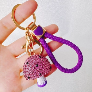 Close-up of purple rhinestone mushroom keychain with gold clasp and braided strap