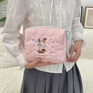 Detailed close-up of pink quilted makeup bag with dog embroidery and zip closure