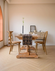 Detail of floral jacquard table runner with tassels on a vintage wooden dining table