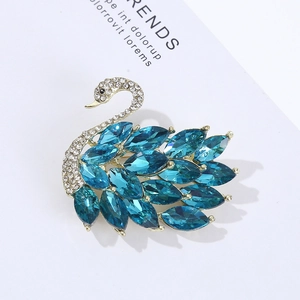 Close-up of elegant gold swan brooch with blue marquise crystals and sparkling rhinestones