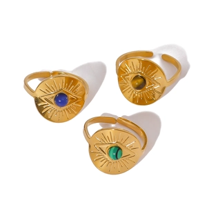 Three vintage gold evil eye rings with blue, tiger eye and green stones on white background