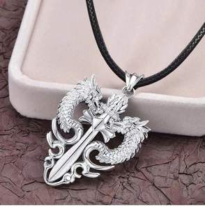 Detail of silver dragon and sword pendant with relief texture on black leather cord