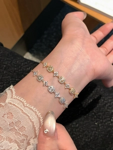 Detailed macro of 18K gold and silver plated bracelets with square zircon flower patterns