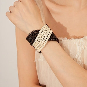 Detail of bohemian multilayered wood bead bracelet in brown and cream on a model's wrist