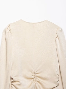 Détail de la chemise ajustée beige avec dos plissé et texture satinée froissée