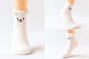 Détail de chaussettes blanches en peluche avec broderie animale et oreilles en 3D