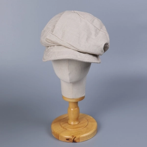 Detailed texture of beige linen blend newsboy cap on a professional display stand