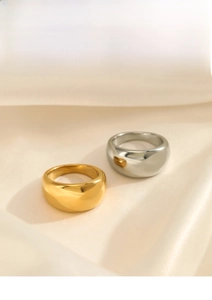 Close-up of polished gold and silver thick dome rings on a textured cream fabric