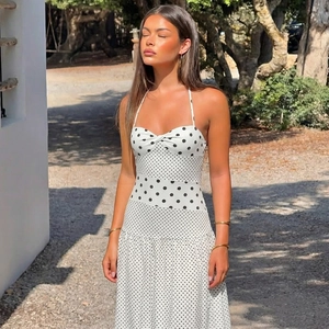 Abito lungo bianco a pois con scollo all'americana e nodo in un ambiente esterno soleggiato