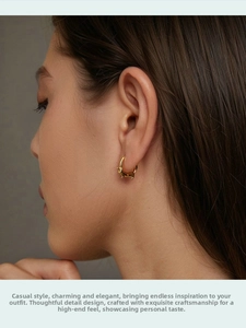 Close-up of golden dachshund puppy hoop earring worn by a model in a minimalist style