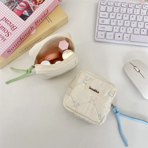 Quilted mini organizer pouch showing storage for lipstick and cosmetics on a desk