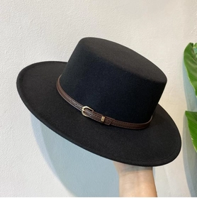 Detail of black wool fedora featuring a brown leather belt band and gold buckle