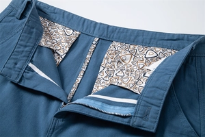 Detail of blue cotton twill shorts with metal zipper and geometric print pocket lining
