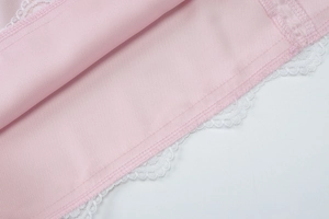 Close-up of pink fabric texture with intricate white lace trim detailing on the dress