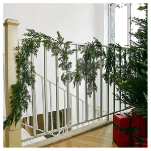 Detailed view of realistic PE pine garland draped over white stairs for festive decoration