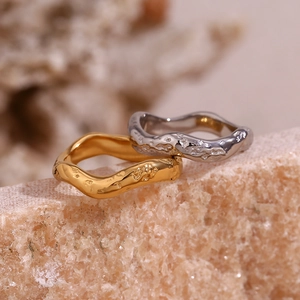 Detail of 18K gold and silver plated hammered texture wave rings on a natural stone