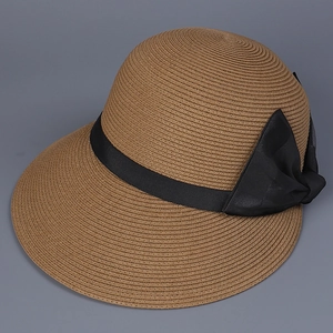 Detailed texture of woven straw sun hat featuring a black ribbon bow in caramel brown