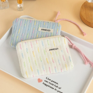 Close-up of woven striped makeup bags with JIMEIZI label and pink zipper pull detail