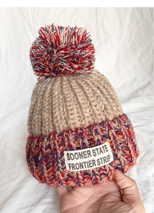 Detailed close-up of kids winter knit hat with colorful pompom and vintage patch