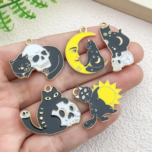 Set of five gothic black cat alloy pendants with moon and skull themes on a palm