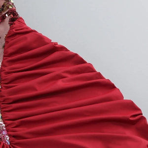 Detail of red halter dress featuring shiny pleated fabric and intricate sequin embroidery
