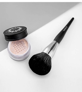 Detail of large fluffy loose powder brush with black handle and loose powder container