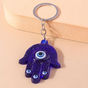 Detailed view of deep blue Hamsa Hand keychain with Evil Eye symbols on a modern stand