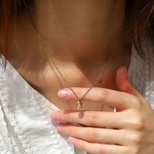 Elegant gold oval pendant necklace with sparkling clear zircon worn on lace clothing