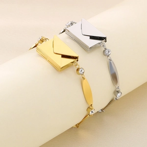 Close-up of gold and silver envelope pendants with crystals on a textured stand