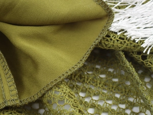 Detail of olive green woven fabric with hollow mesh stitching and white fringe accents