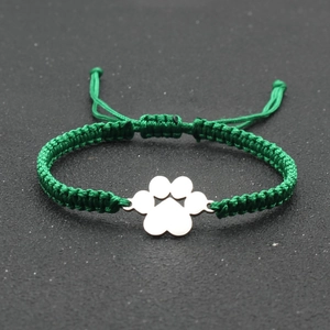 Close-up of green hand-woven adjustable bracelet with a silver dog paw print charm