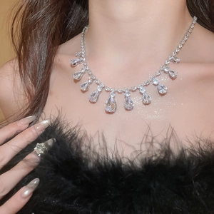 Macro shot of silver zircon teardrop tassel necklace on a model with elegant feathers
