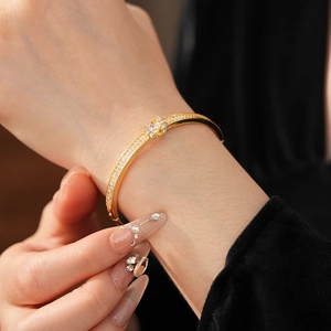 Macro view of gold plated oval bangle featuring U-shaped clasp and pavé zircon settings