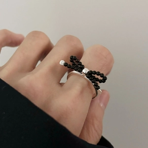 Detail of 925 sterling silver ring featuring a black beaded bow knot on a finger