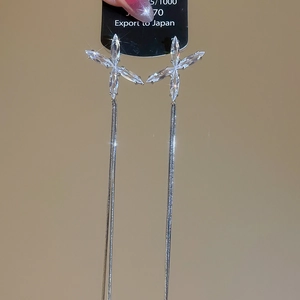 Détail de boucles d'oreilles argentées à longues franges et cristaux de zircone