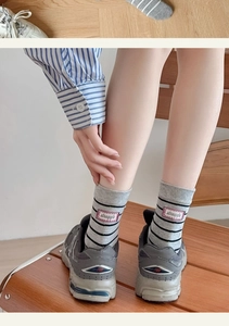 Detail of gray striped cotton mid-tube socks with red struggle label and ribbed cuff