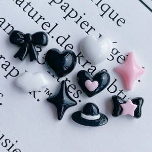 Close-up of DIY resin nail art charms featuring black and pink bows and stars