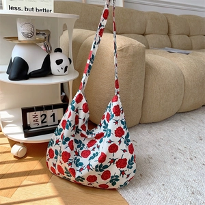 Detail of vintage canvas tote bag with red rose floral print on wooden floor