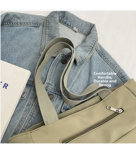 Detail of khaki canvas tote bag featuring a functional front metal zipper and wide handle