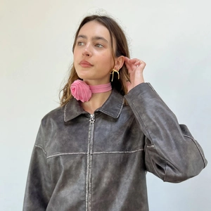 Detail of vintage brown leather jacket with floral choker and gold geometric earrings