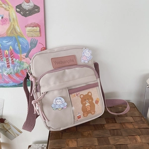 Détail du sac bandoulière en toile avec poche transparente, carte ours et sangle violette
